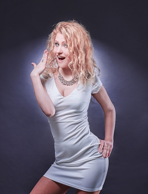 Seksowna młoda blondynka w krótkiej białej sukni. na białym tle na ciemnym tle