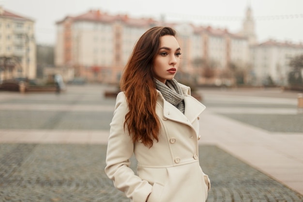 Seksowna młoda kobieta w modnym jesiennym płaszczu ze swetrem, pozowanie w mieście