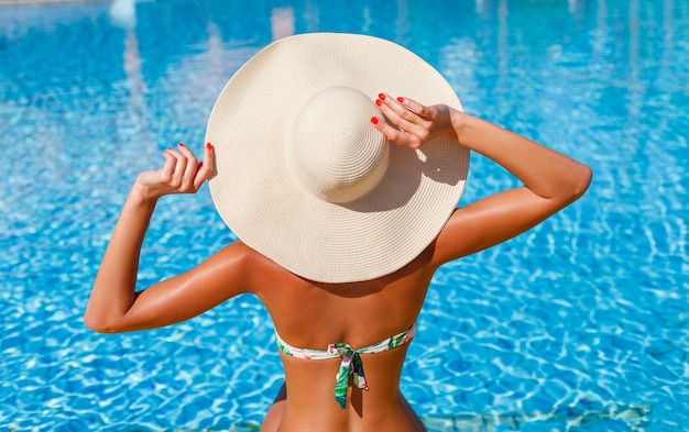 Seksowna piękna modelka w bikini relaksuje się w basenie