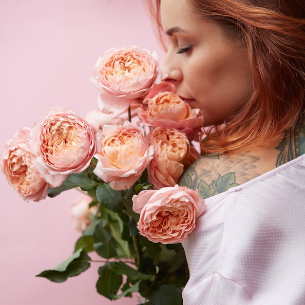 Seksowna rudowłosa kobieta wącha róże w mediach