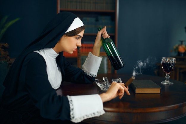 Seksowna zakonnica w sutannie pali cygaro i pije wino, okrutne żądze. Zepsuta siostra w klasztorze, religia i wiara, grzeszni ludzie religijni, atrakcyjny grzesznik