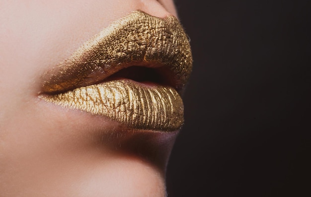 Seksowne usta. Zbliżenie sexy piękne kobiece złote usta na białym tle. Złota szminka.