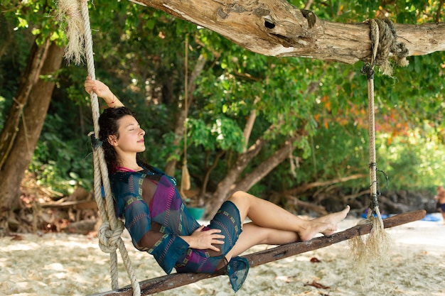 Zdjęcie seksowny dziewczyna model odpoczywa podczas gdy jadący na huśtawce przywiązanej do drzewa na tropikalnej wyspie.