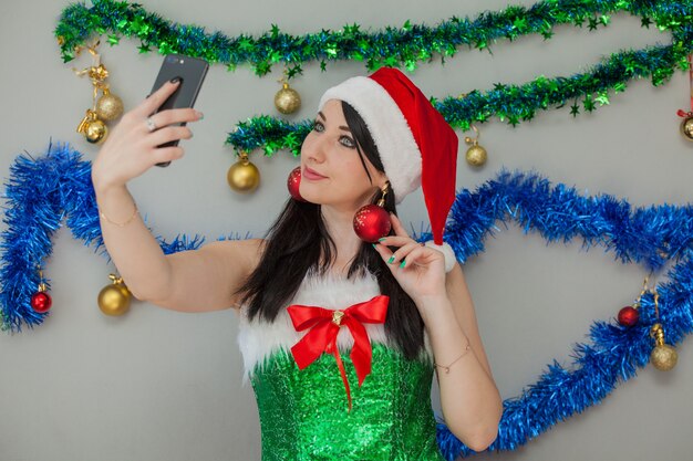 Seksowny pomocnik Mikołaja Namiętna brunetka w stroju elfa z telefonem w dłoniach