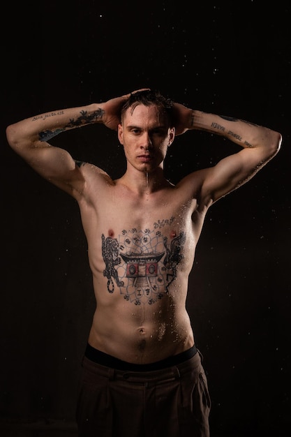 Seksowny zdrowy wytatuowany mężczyzna z kroplami wody na ciele Nagi tors moda męski portret studyjny