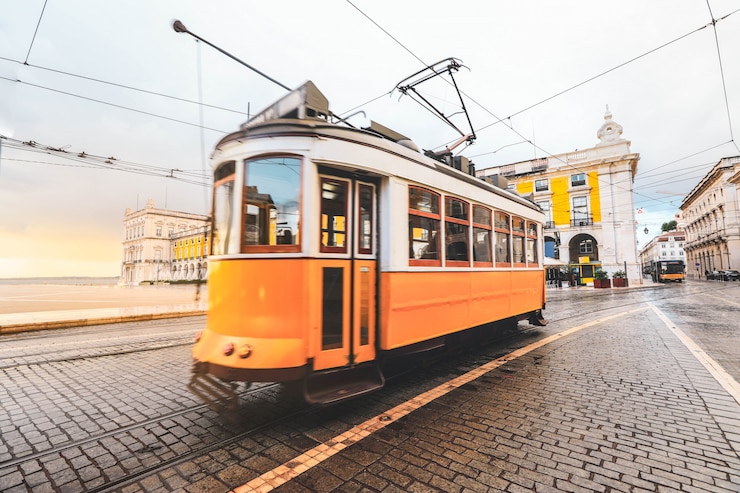 Zdjęcie selekcyjna ostrość na żółtym budynku z zamazanym starym tradycyjnym tramwajowym przelotnym bycity centrum lisbon, portugalia.