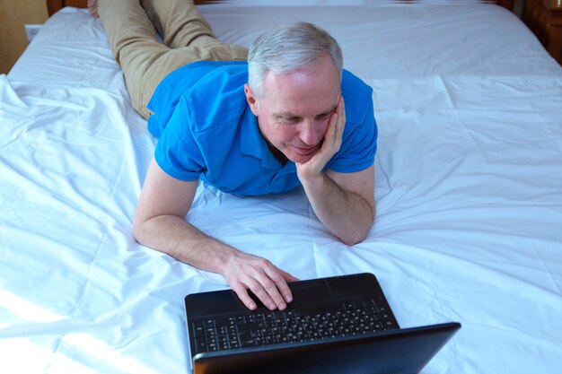 Selektywne fokus na kaukaski mężczyzna leżący w łóżku i oglądać coś na laptopie