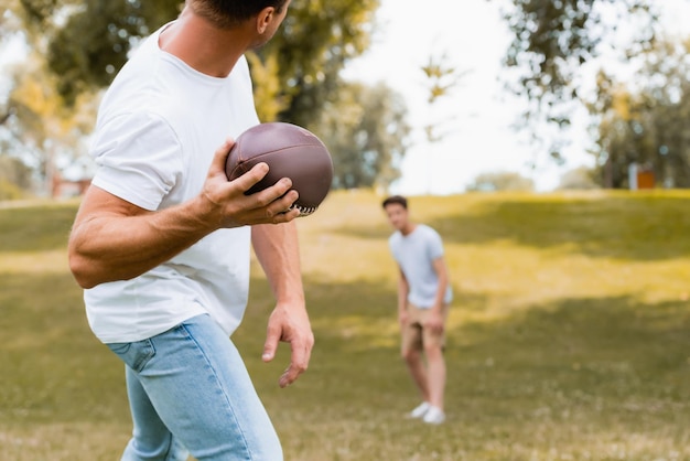 Selektywne skupienie człowieka rzucającego piłkę do rugby synowi w parku