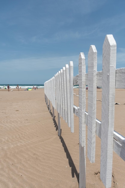 Selektywne skupienie drewnianego ogrodzenia na plaży z morzem w tle