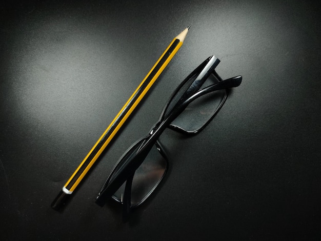 Zdjęcie selektywne skupienie ołówka i okularów na czarnym tle z miejsca na kopię