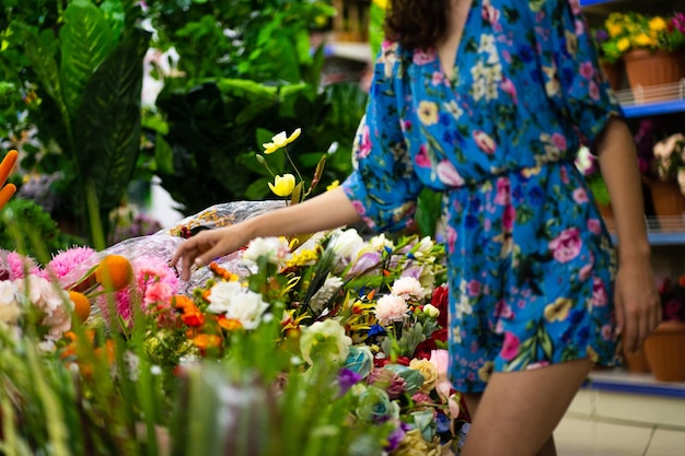 Selektywne skupienie się na kwiatach i roślinach kwiaciarni z kobietą w letniej sukience kupującej
