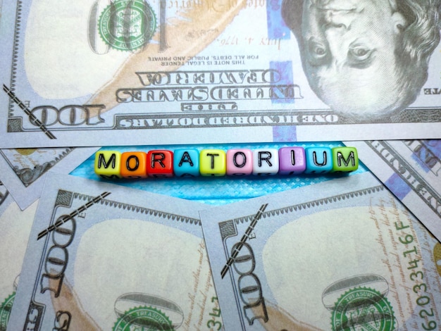 Selektywne skupienie tekstu MORATORIUM z kolorowego sześcianu na masce z banknotem