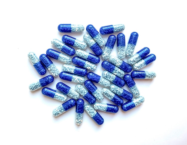 Selektywny fokus, grupa niebieskich tabletek medycznych na białym tle. Pojęcie zdrowia i medycyny.