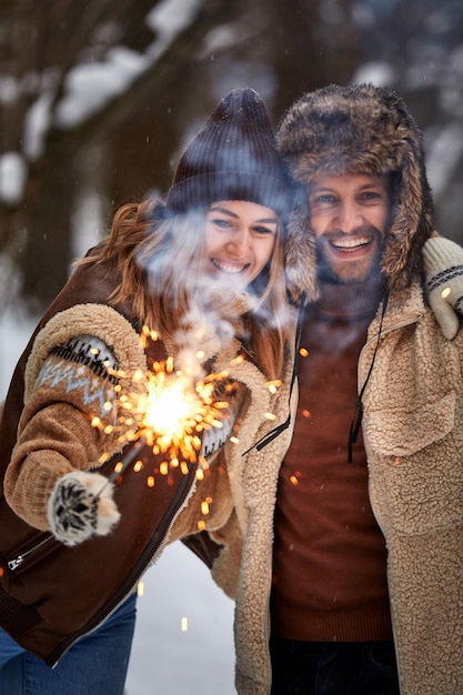 Zdjęcie selektywny fokus para love story w śnieżnym lesie całowanie i trzymanie ognie para zimą natura para świętująca walentynkową randkę