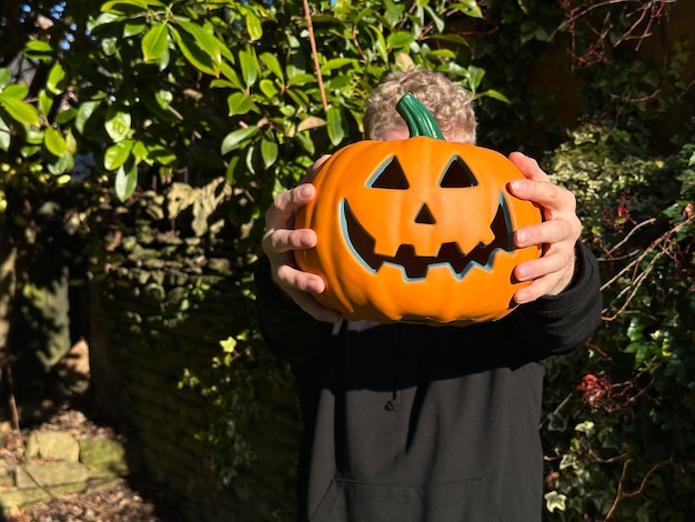Zdjęcie selektywny nacisk na halloween jackolantern dyni nieznany mężczyzna trzyma się do kamery