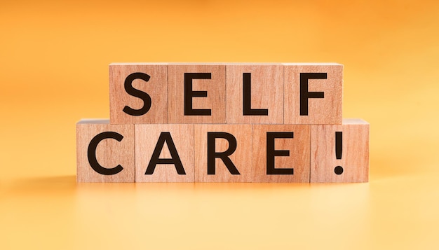 SELF CARE - tekst na drewnianych kostkach na żółtym tle