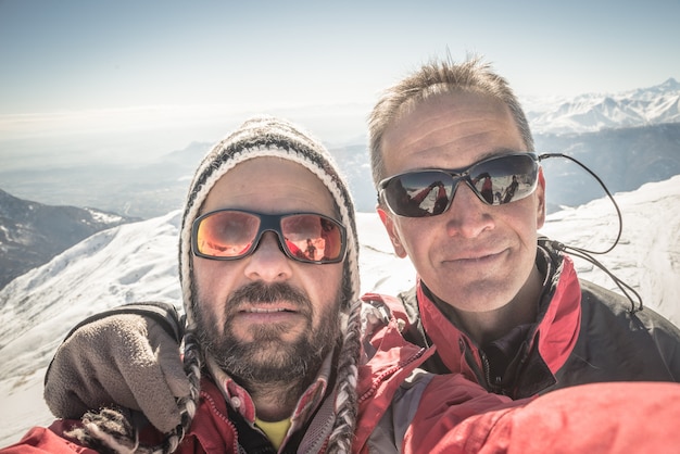 Selfie dwóch alpinistów na szczycie góry zimą
