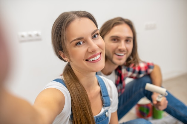 Selfie. Młoda szczęśliwa para siedzi na podłodze i podejmowania selfie