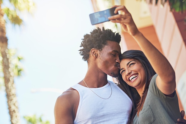 Selfie pocałunek i międzyrasowa para z telefonem w mieście randka i szczęście z pamięcią razem technologia 5g miłość i czarny mężczyzna i kobieta z uczuciem do mobilnego zdjęcia z uśmiechem