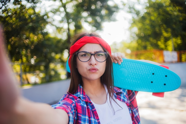 Selfie portret śmieszne młoda kobieta w okularach i czerwoną koszulę w kratę.