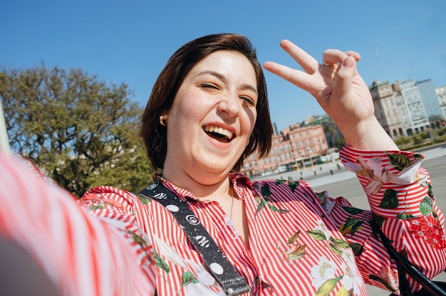 Selfie portret treści Argentyńska kaukaska plus size kobieta na zewnątrz robi znak pokoju i miłości