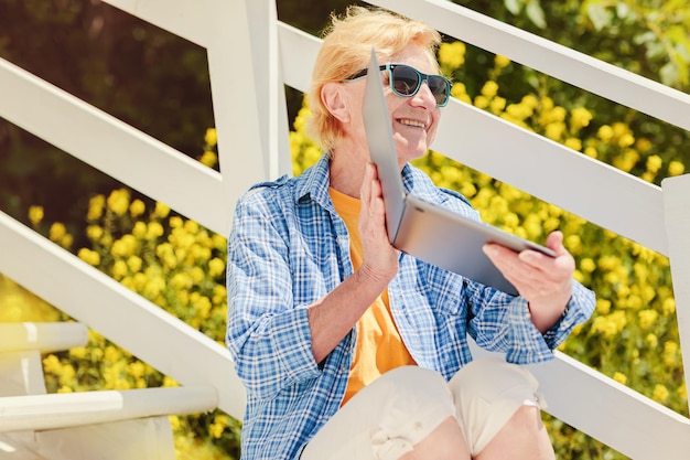 Zdjęcie senior autentyczna kobieta używająca laptopa do kształcenia na odległość na świeżym powietrzu