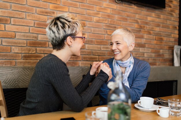 Senior matka siedzi w kawiarni lub restauracji z córką w średnim wieku i ciesząc się w rozmowie.