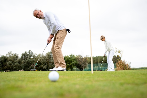 Seniorzy aktywni, grający złoto na polu golfowym i cieszący się wolnym czasem na świeżym powietrzu.