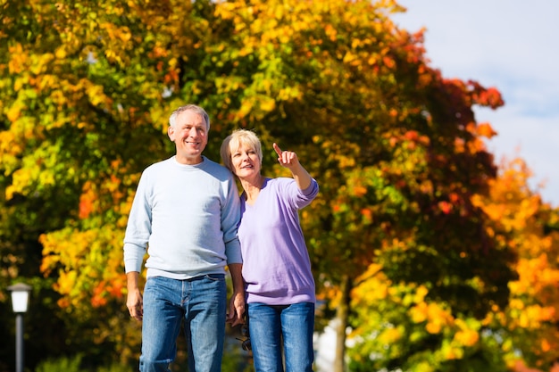 Seniorzy jesienią lub jesienią idą ramię w ramię