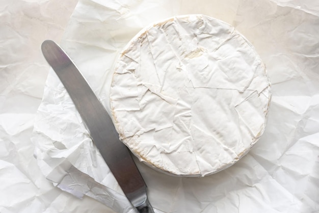 Ser Brie i sztućce kuchenne na białym papierze rzemieślniczym widok z góry