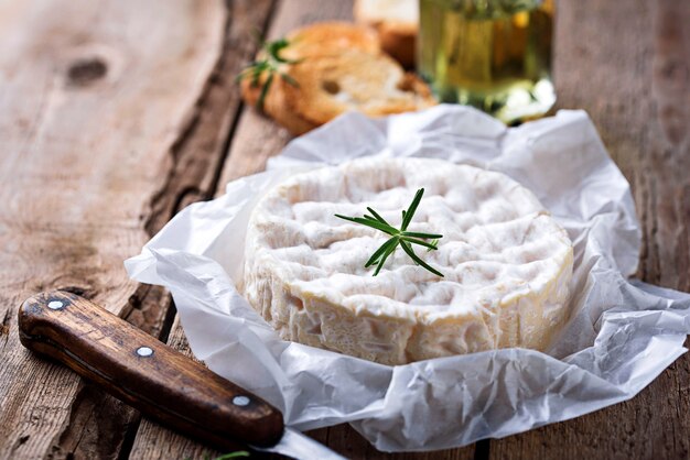 Zdjęcie ser camembert z rozmarynem na drewnianym tle