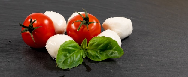 Ser mozzarella, bazylia i wiśnia pomidorowa na płycie łupkowej, miejsce na kopię. Składniki na sałatkę Caprese