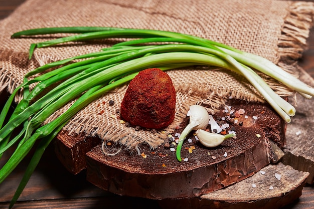 Ser rzemieślniczy z zieloną cebulką i ząbkami czosnku na ściereczce na drewnianej desce