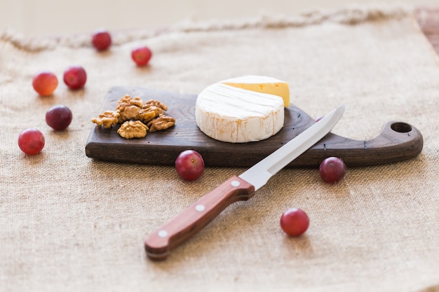 Ser typu Brie. Ser Camembert. Świeży ser Brie na drewnianej desce z orzechami i winogronami