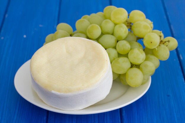 Ser z zielonymi winogronami na białym naczyniu