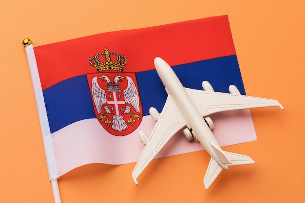 Serbska flaga i samolot zabawka na kolorowym tle, koncepcja na temat podróży do Serbii