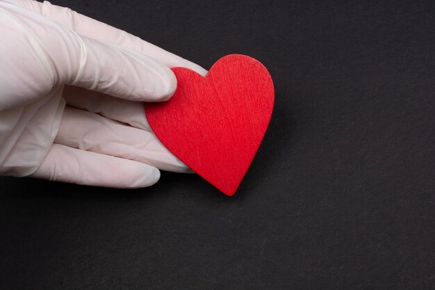 Serca w dłoni z gumowymi rękawiczkami odizolowanymi na czarno
