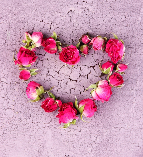 Serce pięknych różowych suszonych róż na starym drewnianym tle