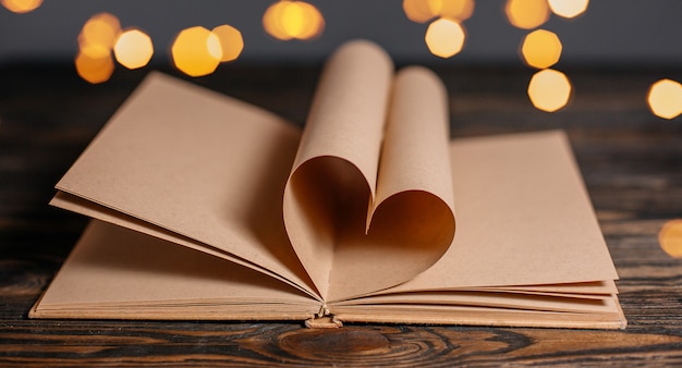 Serce wykonane z arkuszy książek w koncepcji światła, miłości i walentynek na drewnianym stole