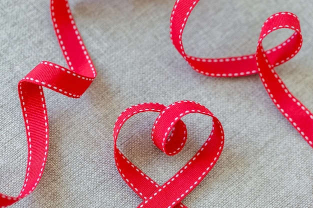 Zdjęcie serce wykonane z czerwonej wstążki na lnianej tkaninie koncepcja dnia walentynek