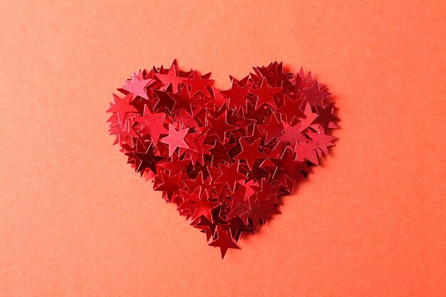 Serce z jasnego konfetti w kształcie gwiazdy na różowym tle Zbliżenie