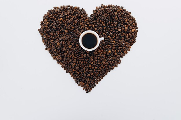 Serce z ziaren kawy i mielonej kawy na białym tle pośrodku to filiżanka