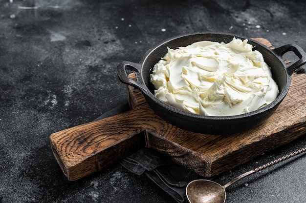 Serek mascarpone na patelni do tiramisu. Czarne tło. Widok z góry. Skopiuj miejsce.