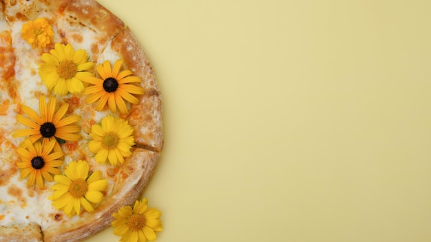 Zdjęcie serowa pizza z kwiatami leży na prostym tle z bliska. zabawne jedzenie, niezwykła porcja