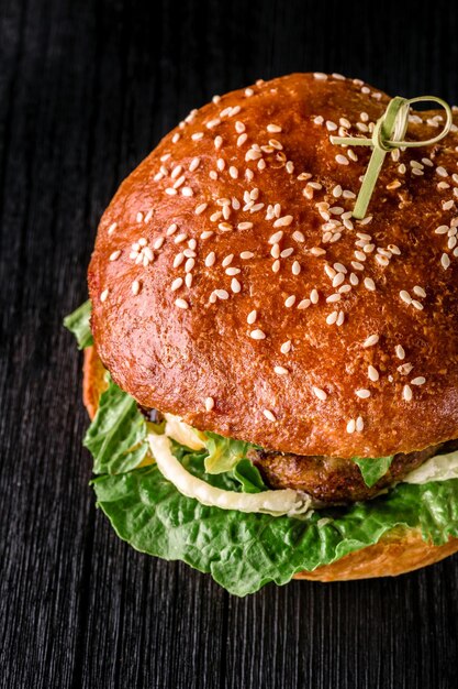 Serowy burger z grillowanym mięsem, serem, pomidorem na ciemnej drewnianej powierzchni. Szablon fast foodów. Prawdziwe zdjęcie. Idealny na reklamę. Zbliżenie. Martwa natura. Hamburger z widokiem z góry