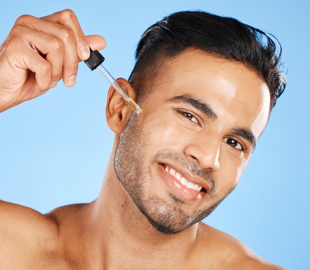 Serum do twarzy mężczyzny lub olejek do brody produktu kosmetycznego do wzrostu zarostu na niebieskim tle studia Portret szczęśliwego młodego arabskiego faceta model płynnej dermatologii i kwasu hialuronowego do kosmetyków do ciała