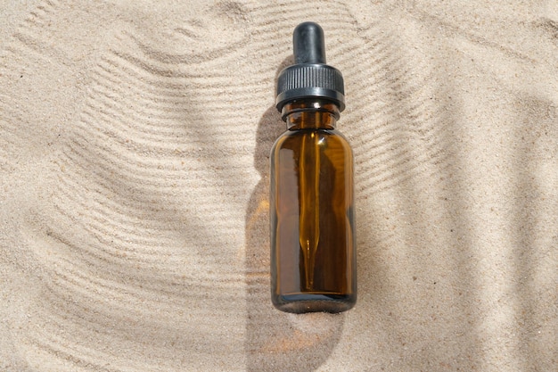 Zdjęcie serum do twarzy szklanej butelki z pipetą na naturalnym tle z piaskiem olejek eteryczny do nawilżania skóry ciała makieta piękna moda kosmetyczna butelka z zakraplaczem z koncepcją pielęgnacji skóry