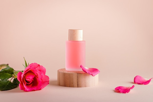 Serum do twarzy z ekstraktem z róży w butelkach do wielokrotnego napełniania na drewnianym podium z minimalnym składem kwiatów róży