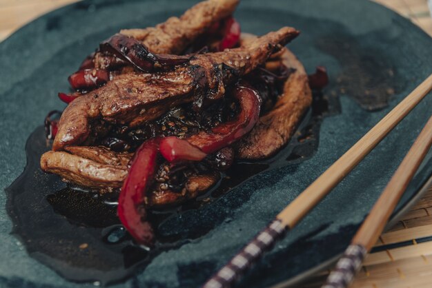 Serwowane paski kurczaka z czerwoną papryką w sosie teriyaki.