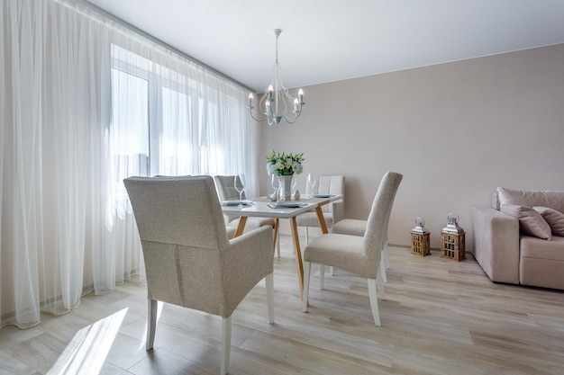 Serwowany stół z bukietem róż we wnętrzu nowoczesnego luksusowego pokoju gościnnego w apartamentach typu studio w minimalistycznym stylu